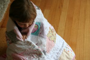 Phoebe wrapped in her baby clothes quilt